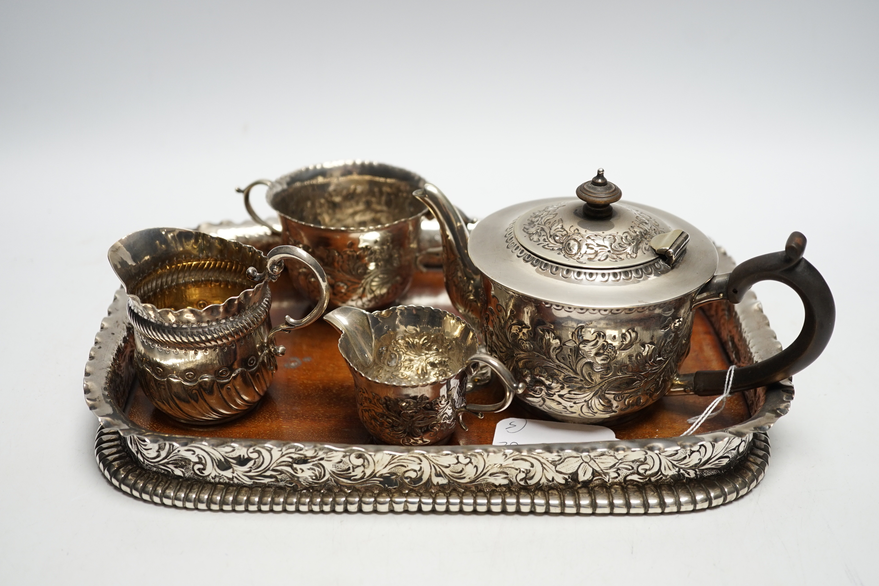 A matched Victorian repousse silver four piece bachelor's tea set, gross 12.8oz and silver plated? mounted wooden tea tray.